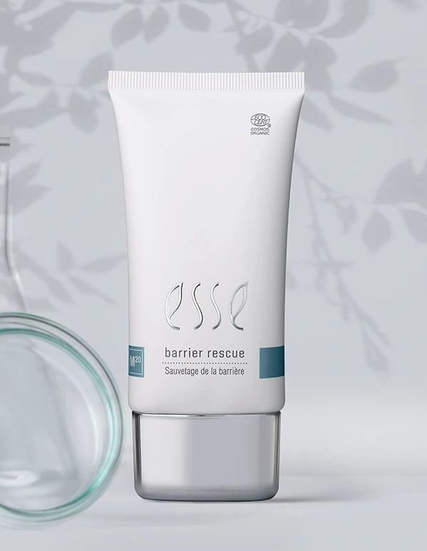A white tube labeled “Import placeholder for 57617” with a silver cap stands against a soft, leafy-patterned background. A glass dish is partially visible on the left side of the image.